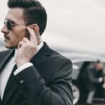 handsome bodyguard of businessman listening message with security earpiece