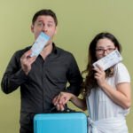 happy-young-couple-tourists-man-woman-holding-air-tickets-suitcase-light