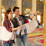 Asian couple backpackers checking map in Thai temple